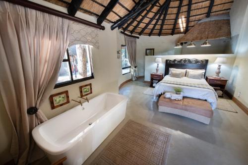 a bedroom with a large bed and a bath tub at Malilule Safaris in Hoedspruit