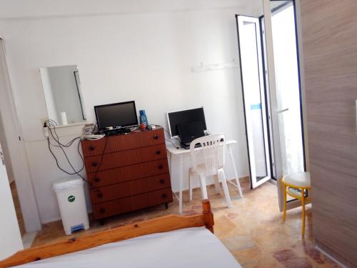 イオス島 チョーラにあるGrandma Vasiliki Rooms To Letのベッドルーム1室(ドレッサー、コンピュータ2台付)