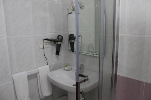 y baño blanco con lavabo y ducha. en Hotel Fernandez, en Sanxenxo