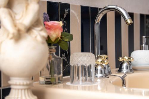 a bathroom sink with a flower in a vase on it at Maison d'hôtes de charme La Rose de Ducey près du Mont Saint Michel in Ducey