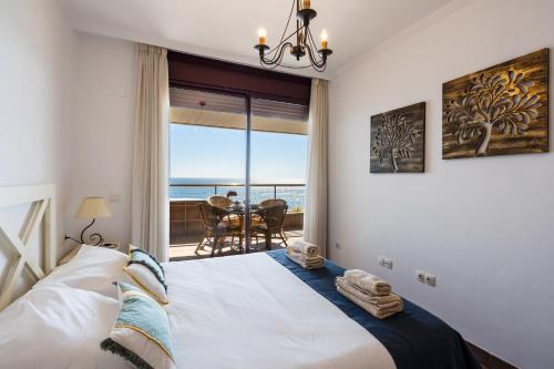 Sur Suites Buena Vista في فوينخيرولا: غرفة نوم مع سرير وإطلالة على المحيط