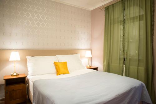 a bedroom with a white bed with a yellow pillow at Szent Anna Panzió in Esztergom