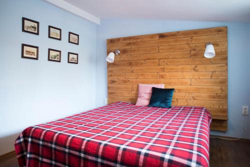 a bedroom with a bed with a red and blue plaid blanket at Szent Anna Panzió in Esztergom