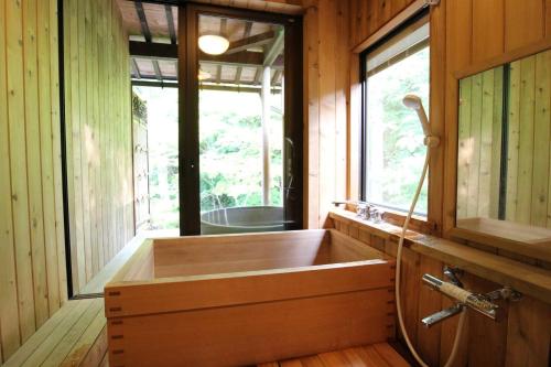 una gran bañera de madera en una habitación con ventana en Shohakuen en Takayama