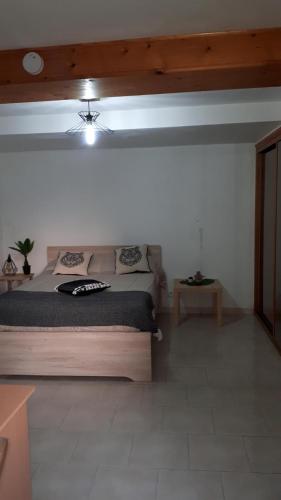 une chambre avec un grand lit et une table dans l'établissement Corse village Calcatoggio location pour 2 pers avec terrasse 5 kms des Plages, à Calcatoggio