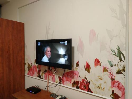 a television on a wall with a floral wallpaper at ApartHotel "Ha-Tzomet" in Bat Yam