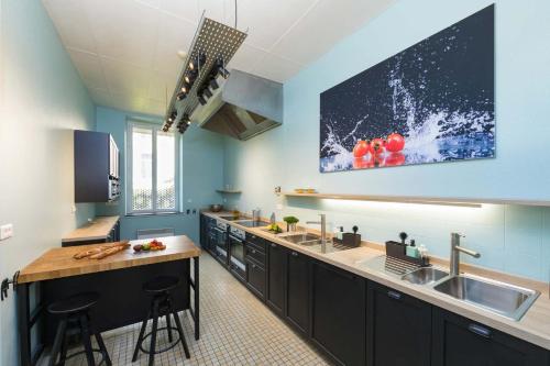 une cuisine avec des placards noirs et une télévision murale. dans l'établissement Un Air de Famille, à Vittel