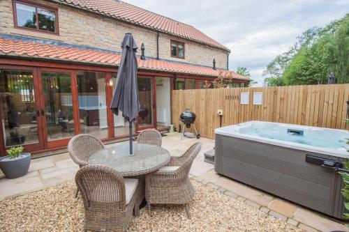 a patio with a table and chairs and a hot tub at High Oaks Grange - Cottages in Pickering