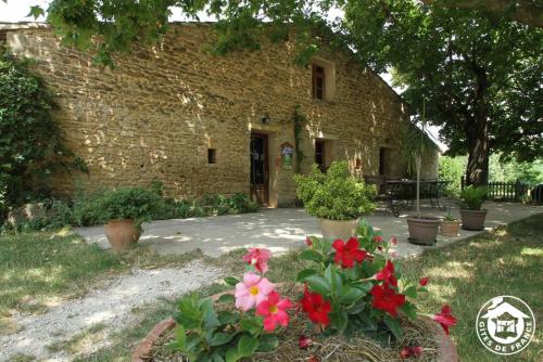 a stone house with flowers in front of it at Roulotte Marcel Chaix Accueil in Étoile-sur-Rhône