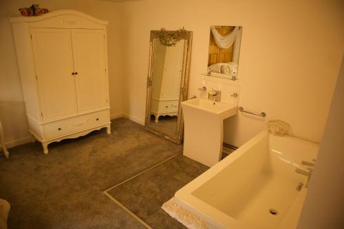 een badkamer met een wastafel, een bad en een spiegel bij Magna in Shilton