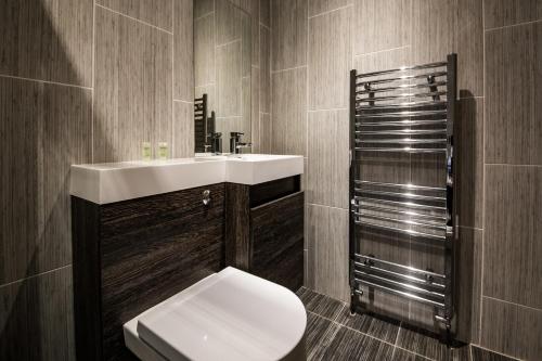La salle de bains est pourvue de toilettes et d'un lavabo. dans l'établissement William's Hillsborough Apartments, à Sheffield