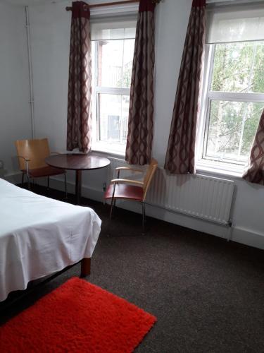 ロンドンにある20 East Tenter Streetのベッド、テーブル、窓が備わる客室です。