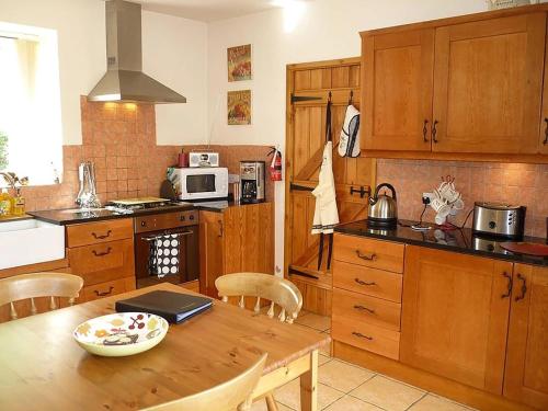 a kitchen with a wooden table with a laptop on it at The Miners Cottage in Whitecroft
