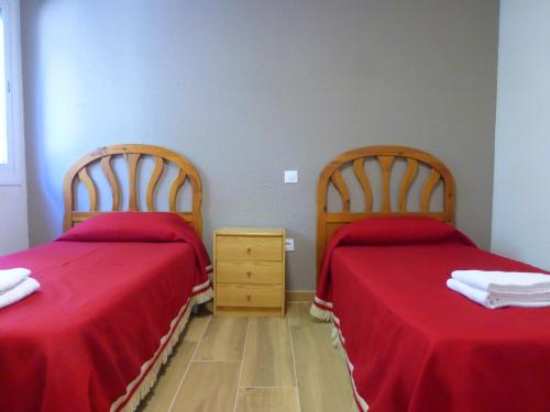 two beds in a room with red sheets at Rentalmar Delfos Playa in Salou