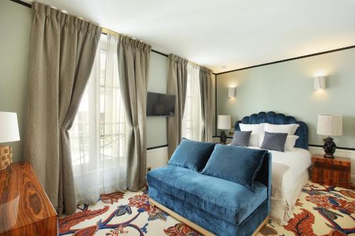 - une chambre avec un lit et un canapé bleu dans l'établissement Le Ferdinand - Le Marais Serviced Apartments, à Paris