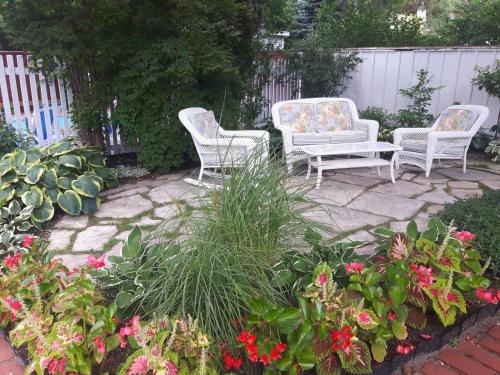 three white chairs and flowers on a patio at Historic Wilson-Guy House in Niagara on the Lake