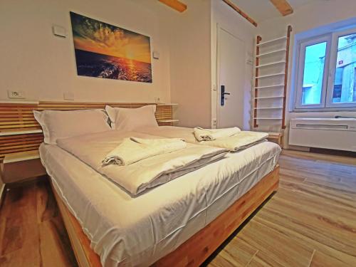 een slaapkamer met een groot bed met witte lakens en een raam bij Ribiška hiša - Old Piran Fisherman's House in Piran