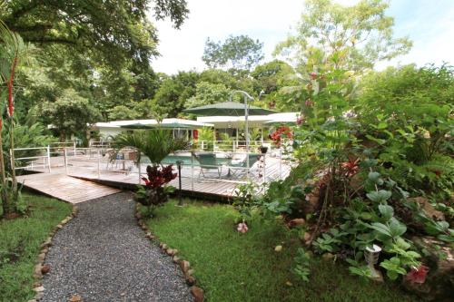 a garden with a deck with tables and chairs at Ojochal Gardens in Ojochal
