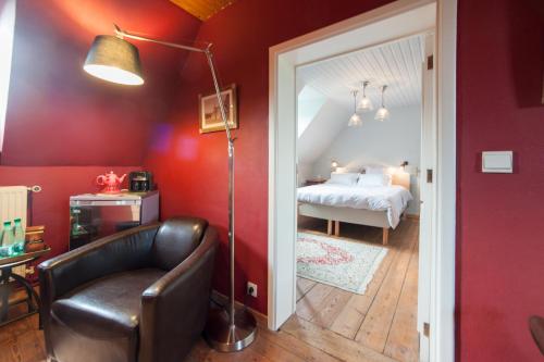 sypialnia z łóżkiem, krzesłem i lampką w obiekcie B&B Cense de la Tour w mieście Nil Saint-Vincent