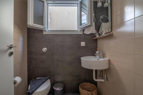 une salle de bain avec un lavabo et des toilettes et une fenêtre dans l'établissement Coco Deluxe Apartment city center of Heraklion, à Héraklion