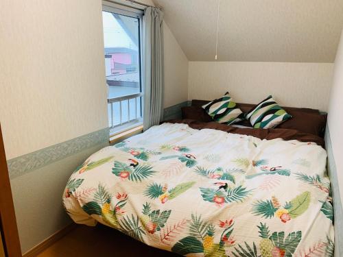 a bed in a small room with a large window at Ecco's House エッコズハウス in Shiraoi