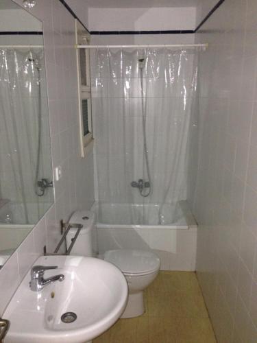 a white bathroom with a toilet and a sink at Càmping Kanguro in San Pol de Mar