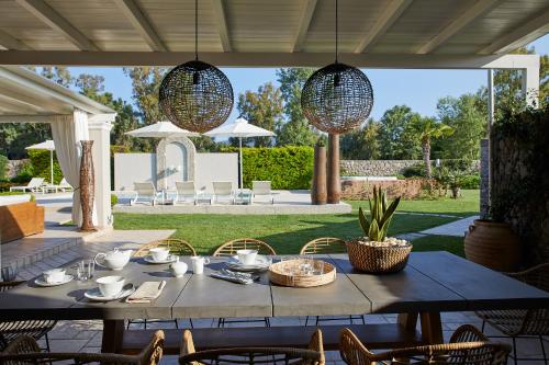 a table and chairs on a patio with two chandeliers at S & O Villas Corfu in Dassia