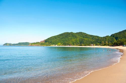 a beach with a group of people swimming in the water at Atena Praia Hotel in Boicucanga