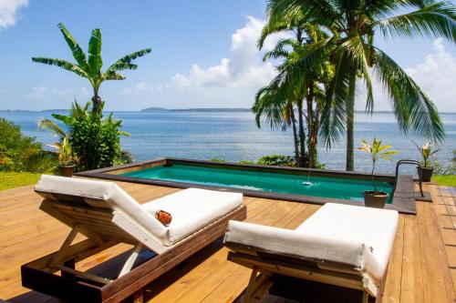 a deck with chairs and a swimming pool and the ocean at El Caribeo in Bocas del Toro