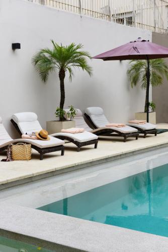 a swimming pool with lounge chairs and an umbrella at Argenta Suites Belgrano in Buenos Aires