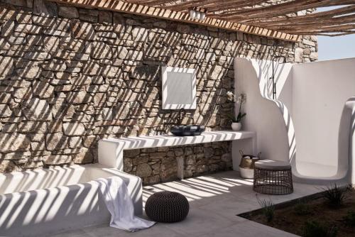 a patio with a stone wall with a sink and a mirror at Katikies Villas Mykonos in Elia Beach