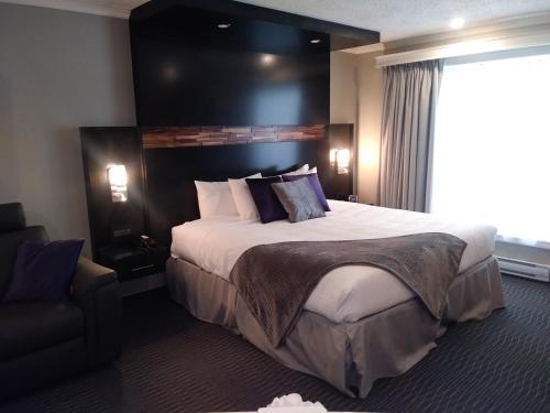 a hotel room with a large bed and a chair at Hotel des Eskers in Amos