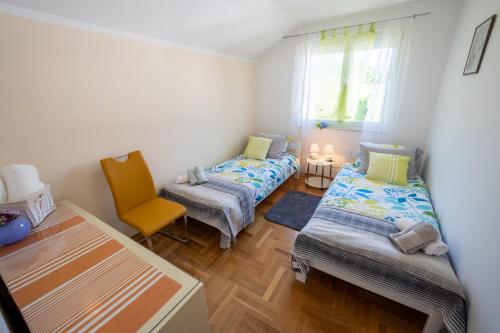 a small room with two beds and a chair at Stella House Mrežnica in Duga Resa