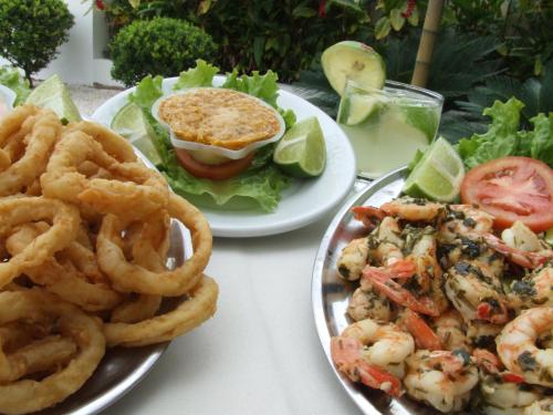 two plates of food with shrimp and a sandwich and onion rings at Atena Praia Hotel in Boicucanga