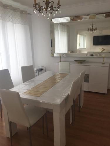 - une table à manger blanche et des chaises dans la cuisine dans l'établissement maison proche du Mont Saint Michel, à Pontorson