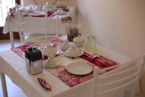una mesa con platos blancos y vasos. en LA CASA DELL'ORSO en Ciampino