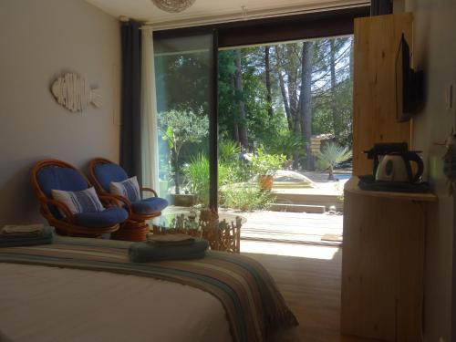 a bedroom with a bed with blue chairs and a window at La Grange Océane SPA & Piscine chauffée en saison in Lège-Cap-Ferret