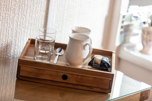 a wooden tray with glasses and a vase on a table at Ladysmith Guest House in Ullapool