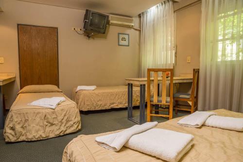 Habitación con 3 camas, mesa y TV. en Hotel Cordon Del Plata en Mendoza