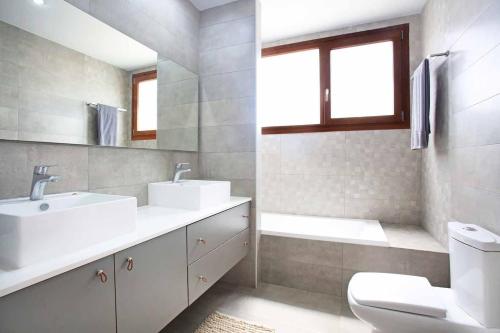 Un baño con dos lavabos y un inodoro y una ventana. en Villa Elpida, Kokkini Hani, en Kokkíni Khánion