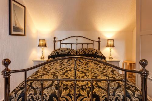 a bedroom with a black bed with two lamps at Ladysmith Guest House in Ullapool