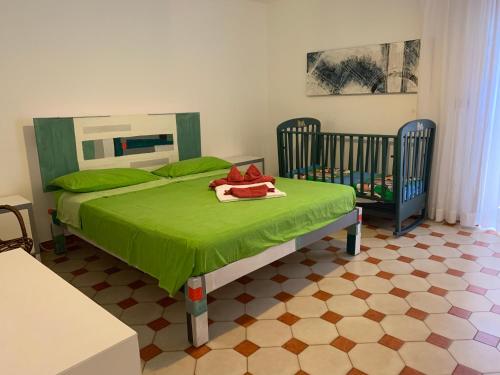una camera con un letto verde e due lettini di Casa Manni Torre Suda a Racale