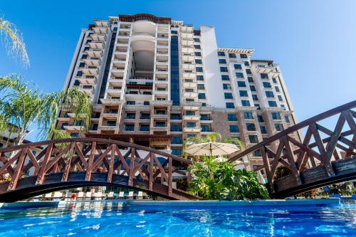 a bridge over a pool in front of a tall building at Crocs Resort & Casino in Jacó