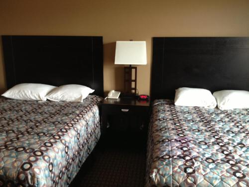 a hotel room with two beds and a lamp at Super 8 by Wyndham Odessa TX in Odessa