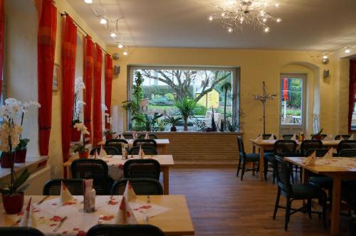 un restaurant avec des tables et des chaises et une grande fenêtre dans l'établissement Ferienwohnungen im Gasthaus Zur Grünen Wiese, à Sebnitz