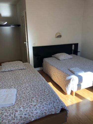 Dos camas en una habitación pequeña con 3 estrellas que dice que es lo que dice en VILLA HOTEL, en Malesherbes