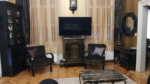 a living room with a television and two chairs and a table at Boudoir Budapest Apartment in Budapest