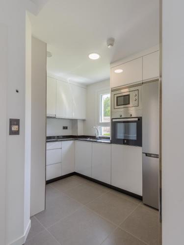 a white kitchen with white cabinets and appliances at Apartamentos Onzamar in Sanxenxo