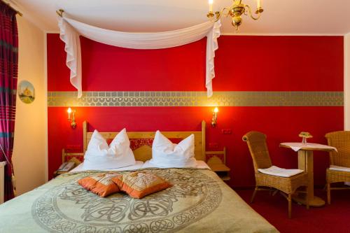 a bedroom with red walls and a bed with two pillows at Hotel & Ferienwohnungen Bohlenblick in Saalfeld