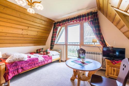 1 dormitorio con cama, mesa y TV en Willa Cetynka, en Zakopane